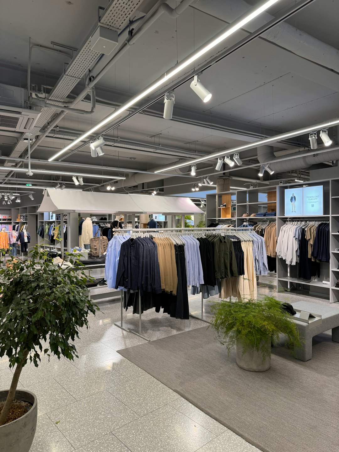 Moderner Modegeschäft mit Kleiderständern und Werbebildschirm.