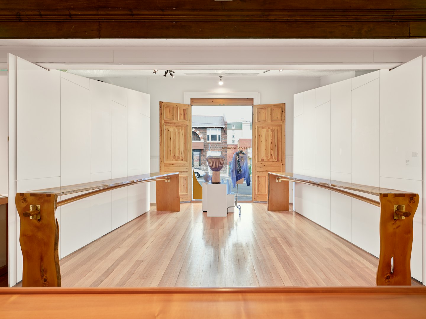 Galerieinterieur mit Holztischen und Auslagen.