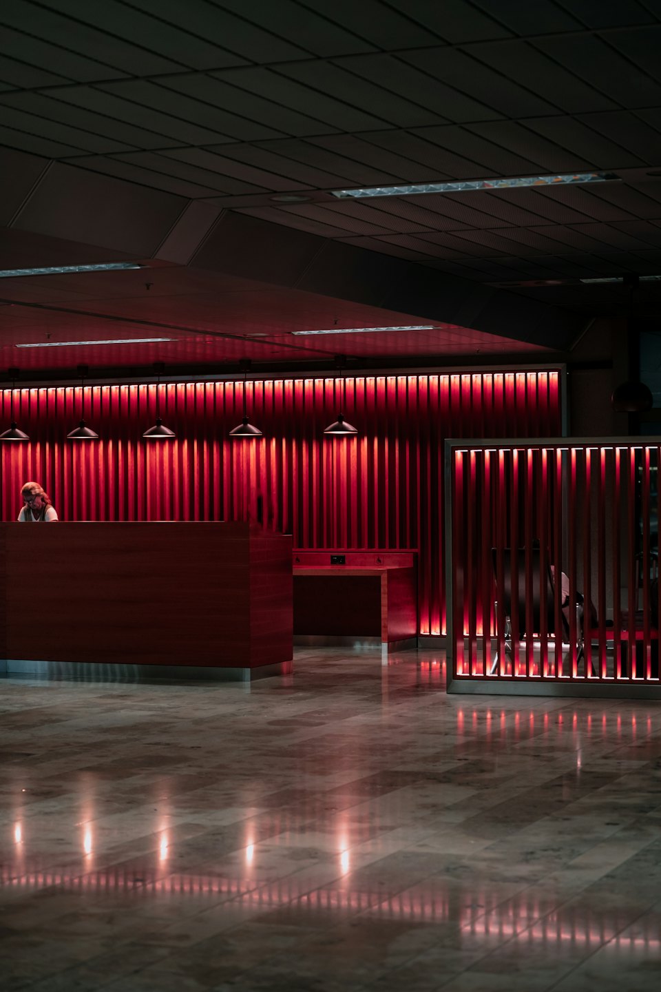 Eine Rezeptionistin sitzt an einem Schreibtisch in einer modernen Bürolobby.