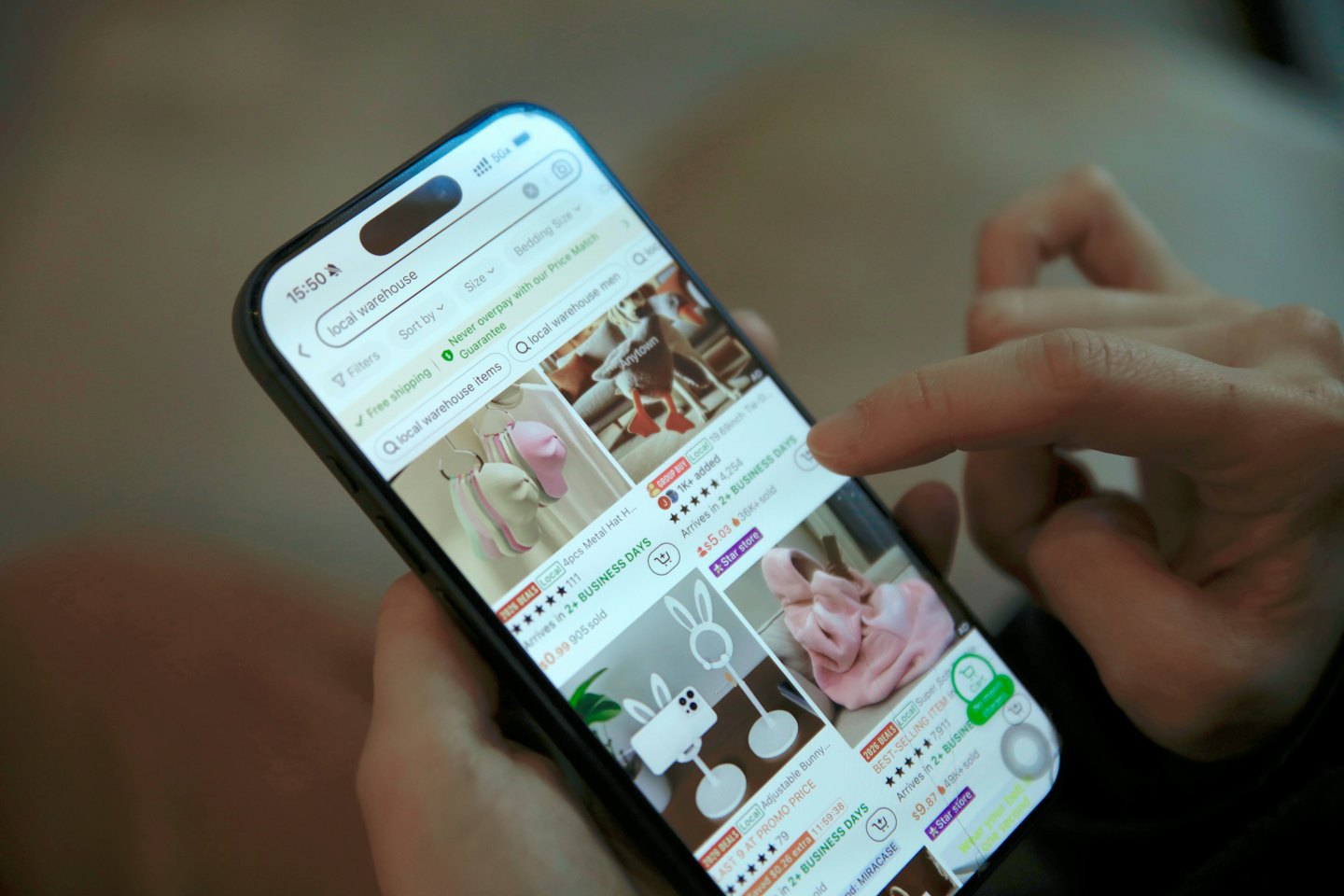 Hände tippen auf eine Online-Shopping-App auf einem Smartphone.
