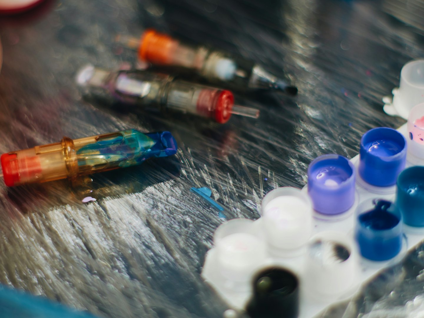 Bunte Tattoo-Nadelmodule und kleine Becher mit Tattoo-Farbe.
